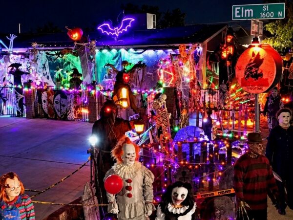 Halloween yard display featuring skeletons, colorful lights, cobwebs and horror movie characters, including Pennywise the clown, outside a Visalia home.