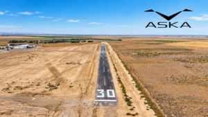 Aerial view of Eagle Field’s runway near Firebaugh, California, surrounded by agricultural land, with an AI-enhanced image and ASKA company logo overlaid in the sky.
